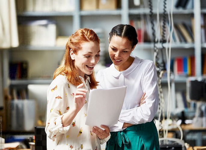 two business woman standing and looking over papers