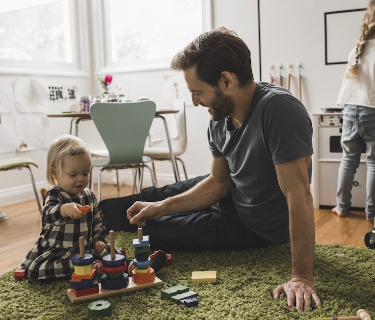 Father and daughters playing with toys in playroom at home