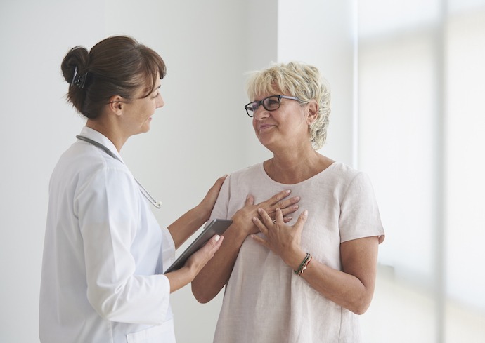 Mujer médico dando buenas noticias a una paciente madura.